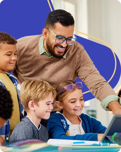 A teacher helps three young students, two boys and one girl, as they look at a tablet together in a classroom.