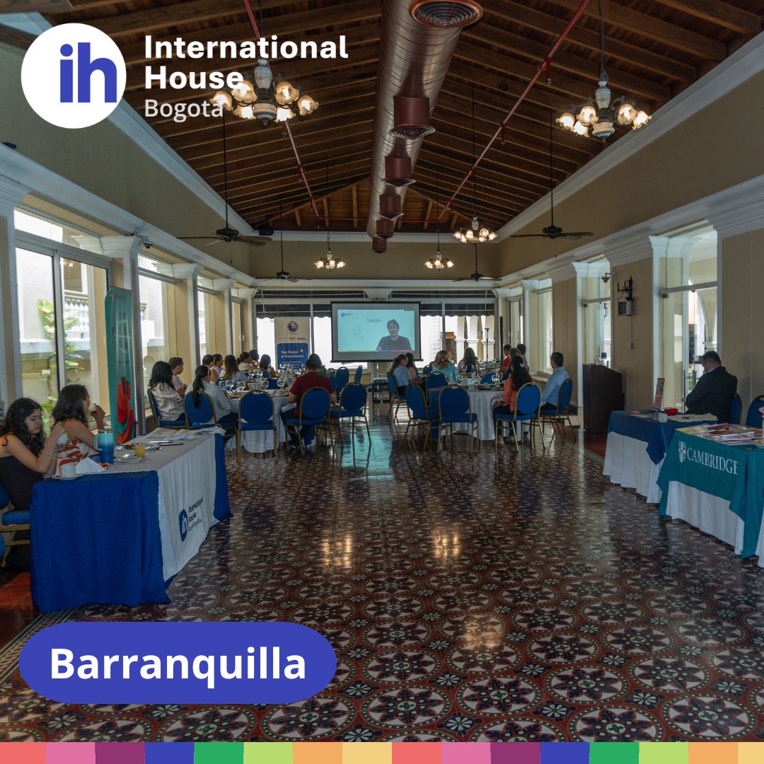 A conference room with people seated at tables, a presenter at the front, and a screen displaying a presentation. "International House Bogota" and "Barranquilla" labels are visible.