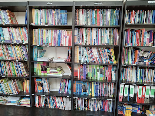 Bookshelves filled with neatly arranged books and folders, with some books stacked horizontally and a few open spaces on the shelves.