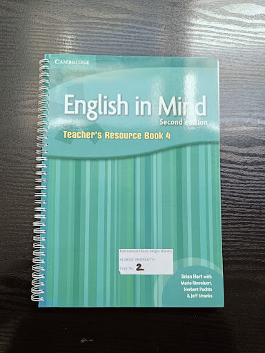 Spiral-bound book titled "English in Mind Second Edition: Teacher's Resource Book 4" on a dark wooden surface.