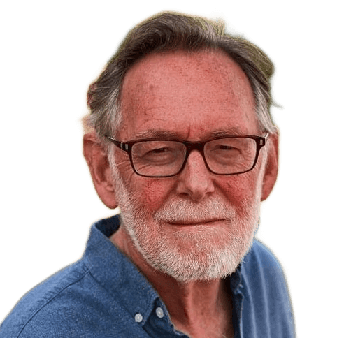 Older man with gray hair, beard, and glasses, wearing a blue shirt, looking at the camera against a plain white background.