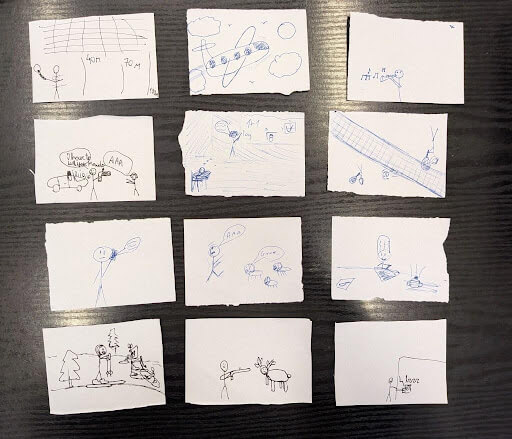 Twelve small pieces of paper each show different blue-ink stick figure drawings, depicting various activities and scenes on a dark surface.