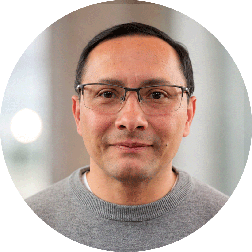 A man with dark hair and glasses smiles at the camera.
