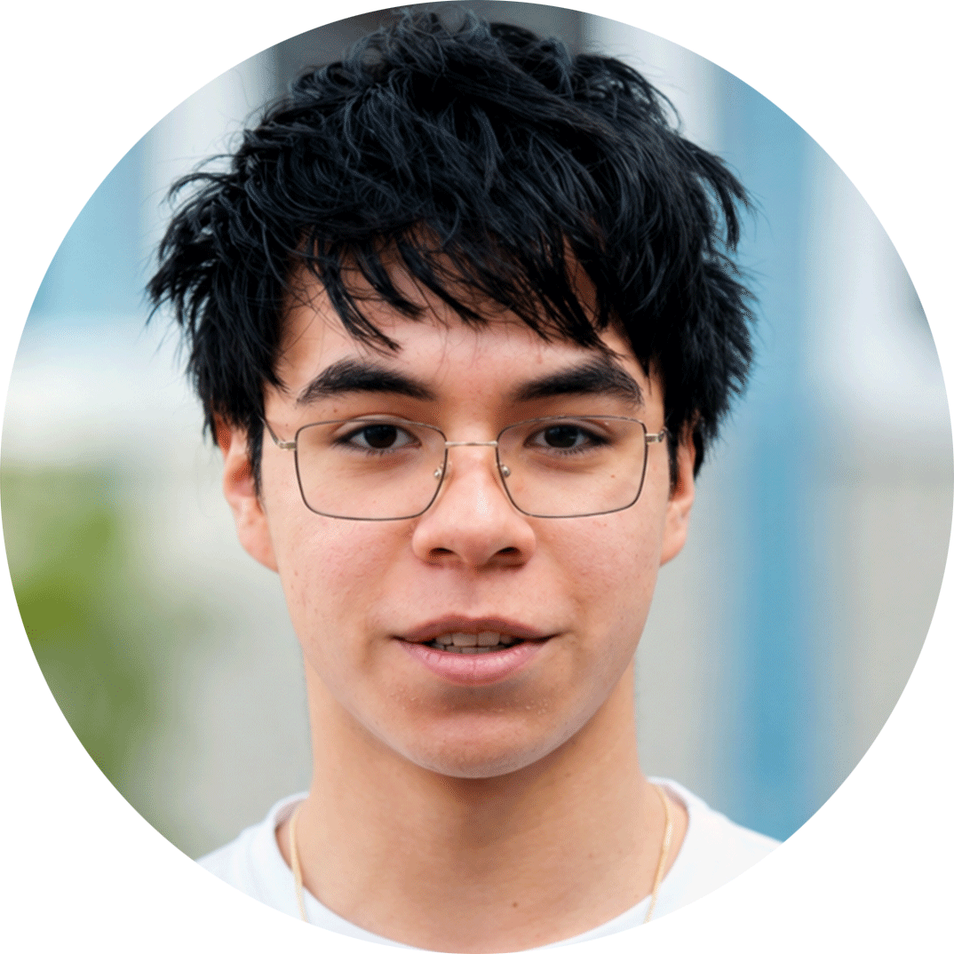 A young person with dark hair and square glasses smiles at the camera